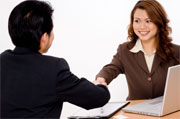 A smiling businesswoman shakes hands with a young businessman